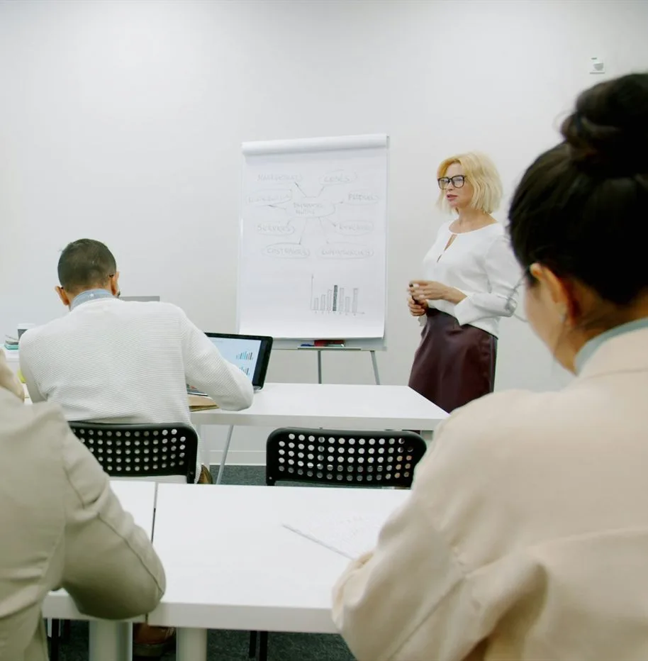 Online tanfolyamok – hallgatók laptopokkal a tantermünkben, elöl oktató a flipchart mellett